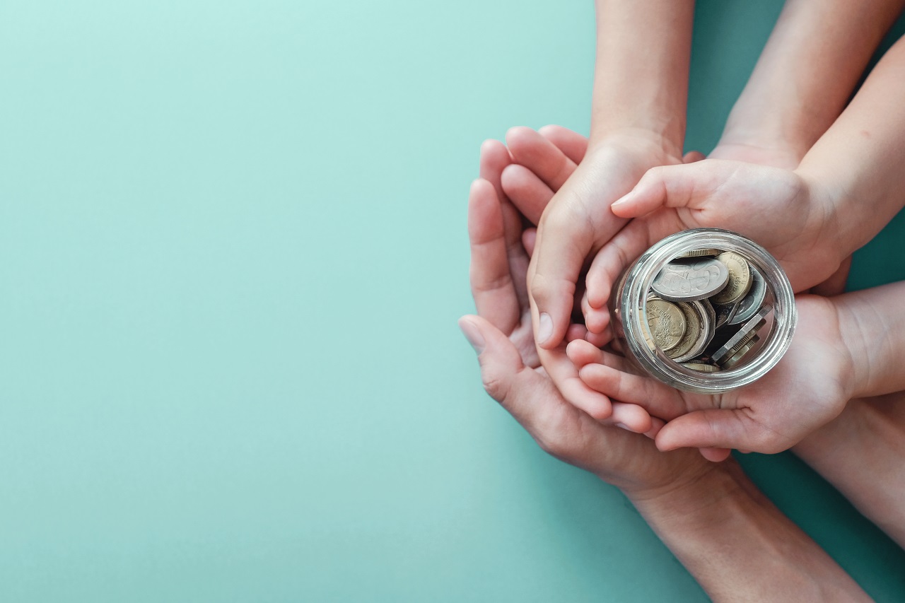 A parent and child holding a jar of their savings