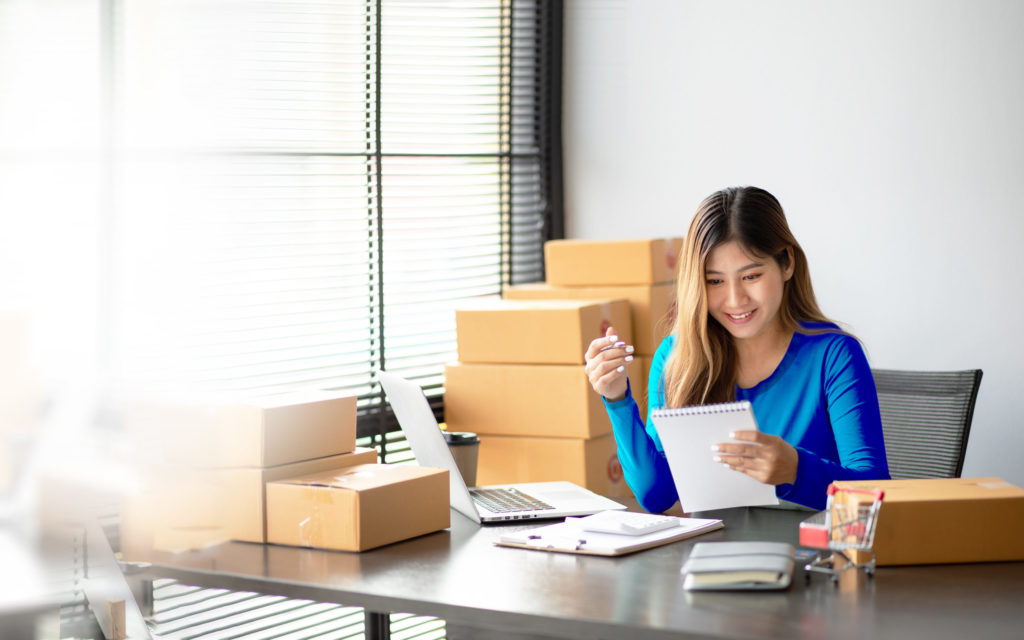A woman sitting at a table with boxes and a laptop