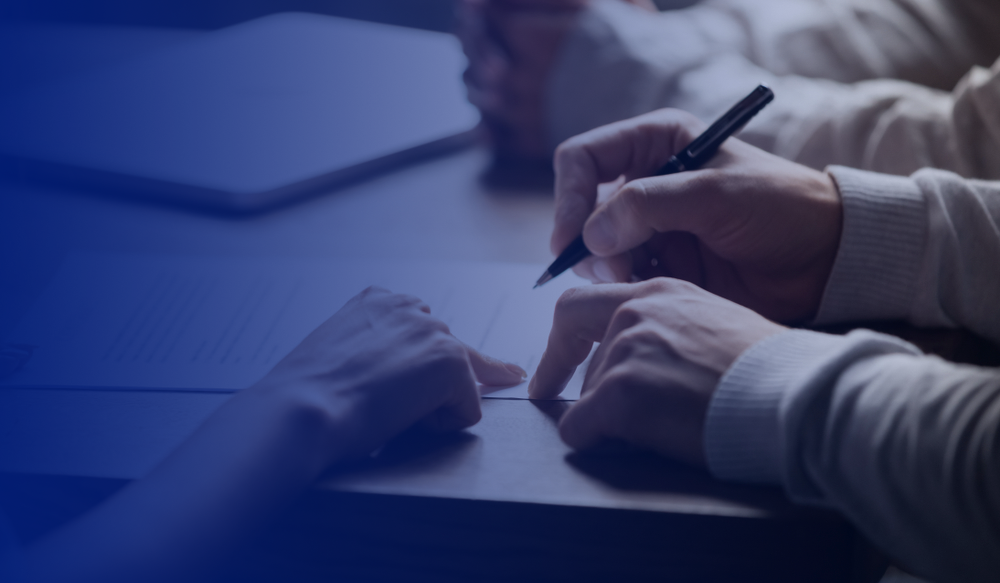 Two people sitting at a table with papers and a pen