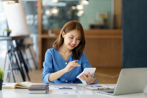 Young Asian businesswoman using a calculator to calculate business principles.