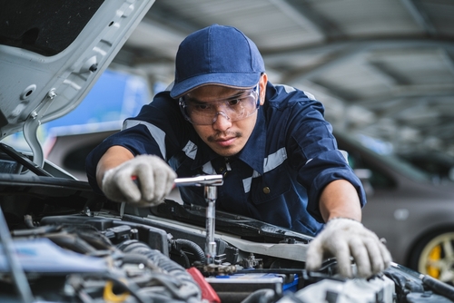 Portrait of an Asian mechanic checking the safety of a car. Maintenance of damaged parts in the garage. Maintenance repairs.
