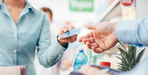 Woman at the supermarket checkout, she is paying using a credit card, shopping and retail concept