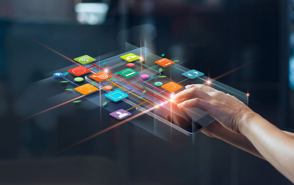 A pair of hands holding a tablet with graphic icons pertaining to digital media and marketing.