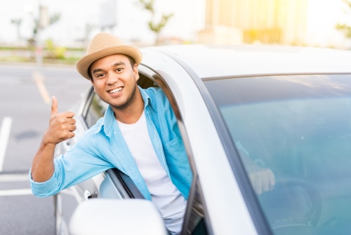 Man driving while giving a thumbs up