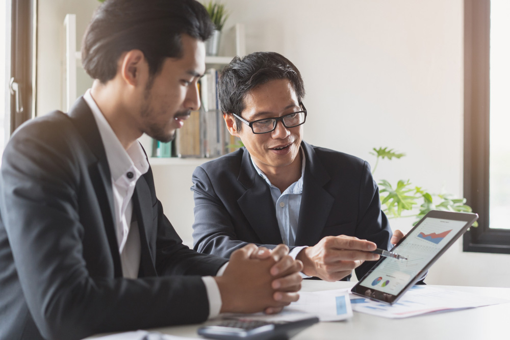 Two Asian men working on finances.