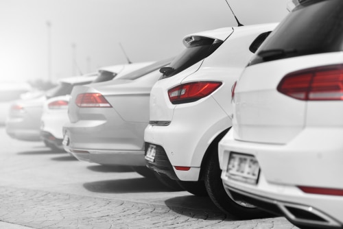 A row of white and silver cars in a parking lot. This is to illustrate our car buying checklist.
