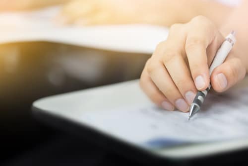 Closeup of a right hand holding a mechanical pencil answering a form