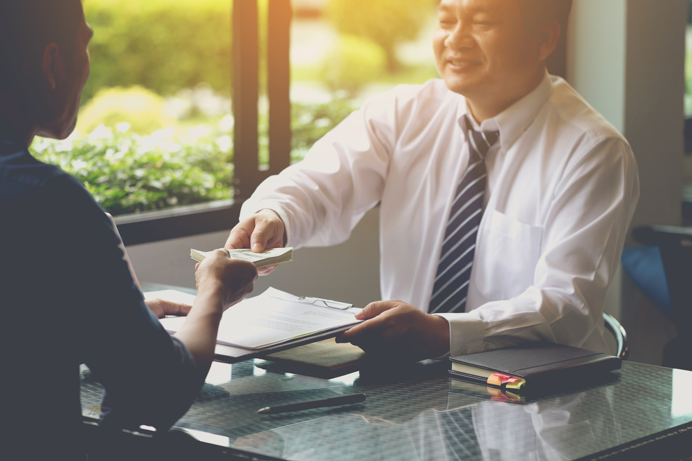 man receiving money from a man in a corporate attire